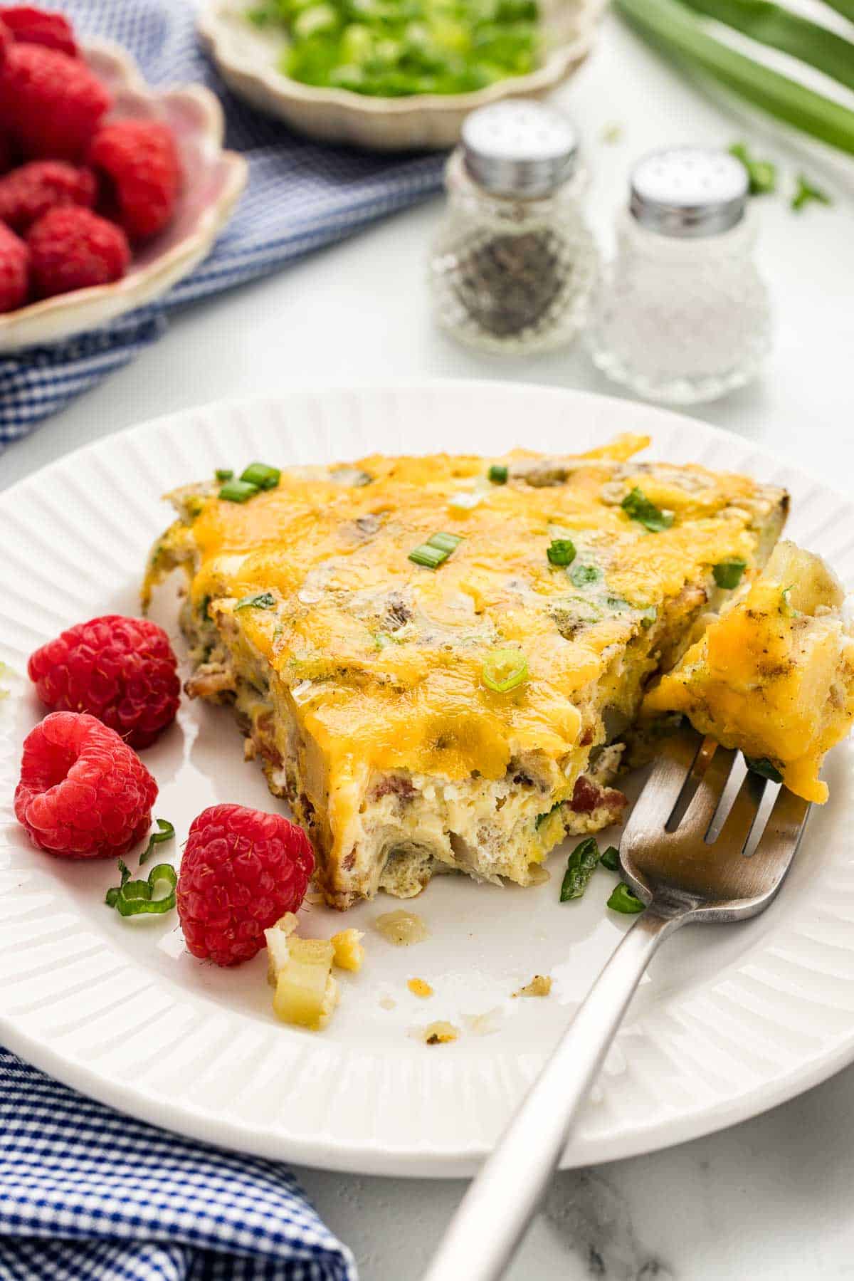 A half-eaten slice of breakfast bake on a plate with a fork.