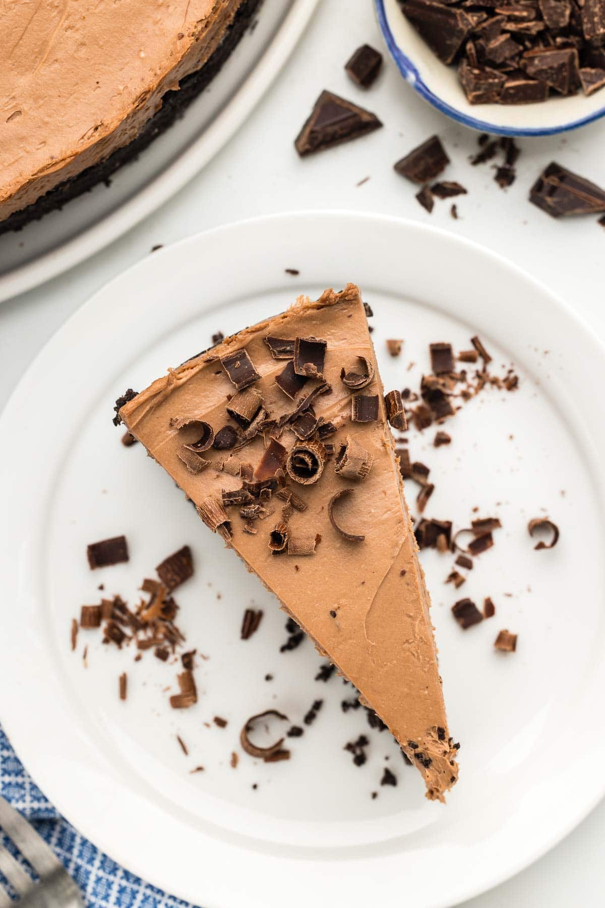 Overhead of a serving of chocolate cheesecake with chocolate shavings on top.