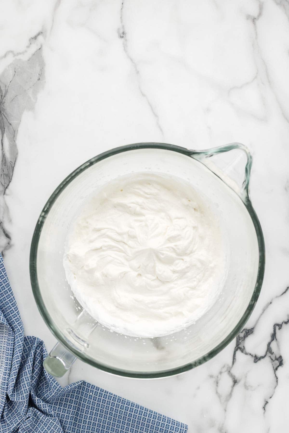 A large dish of whipped cream on a marble counter.