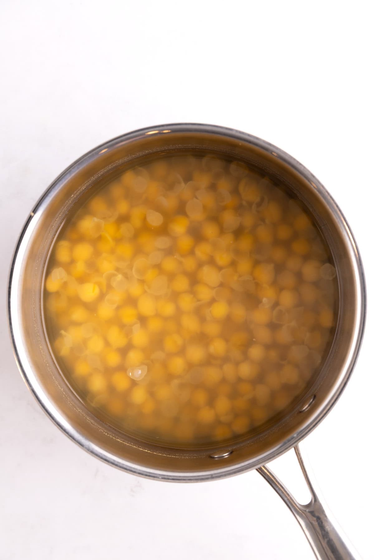 Chickpeas cooking in a pot filled with water.