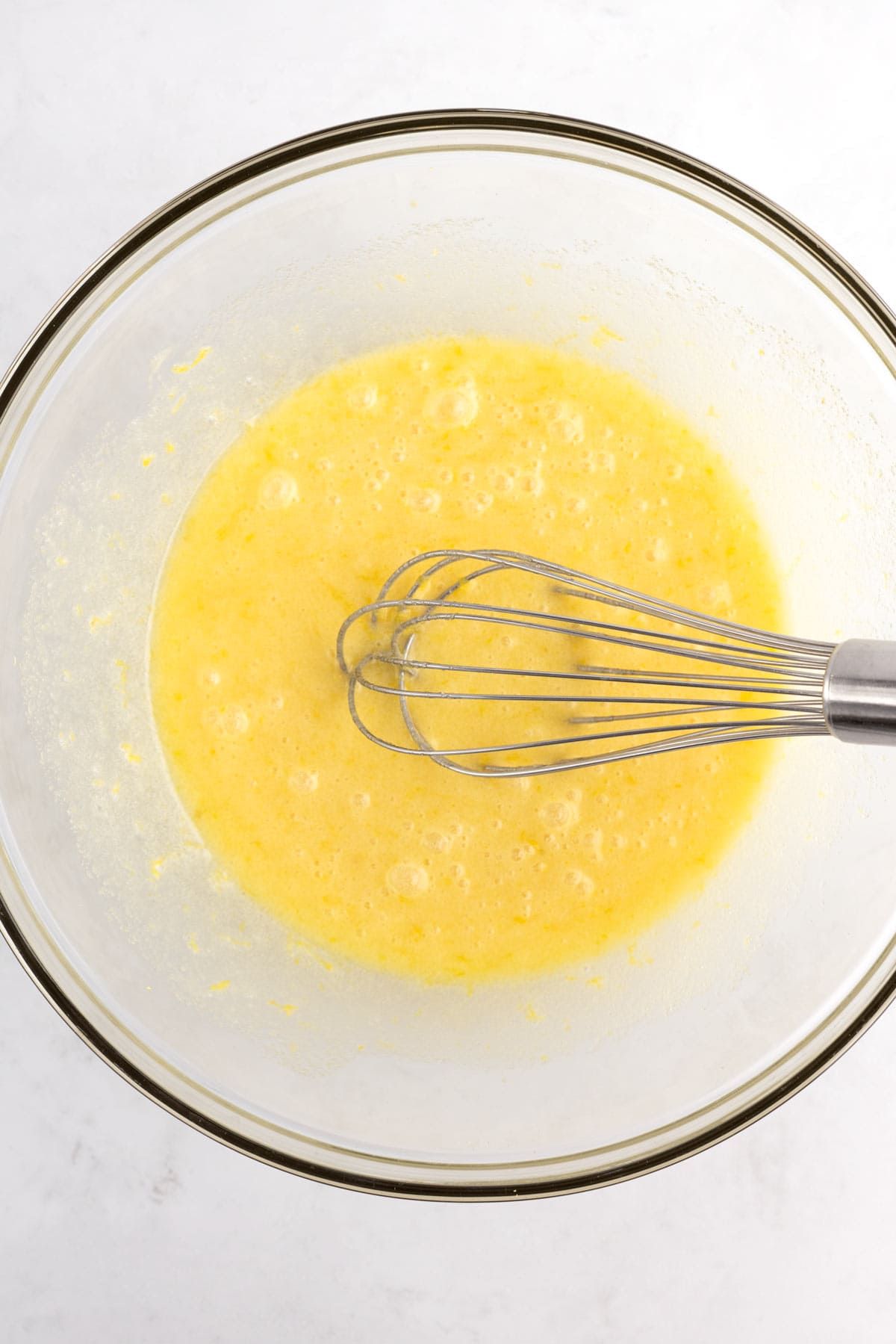 Butter and sugar mixed together with a whisk in a glass bowl.