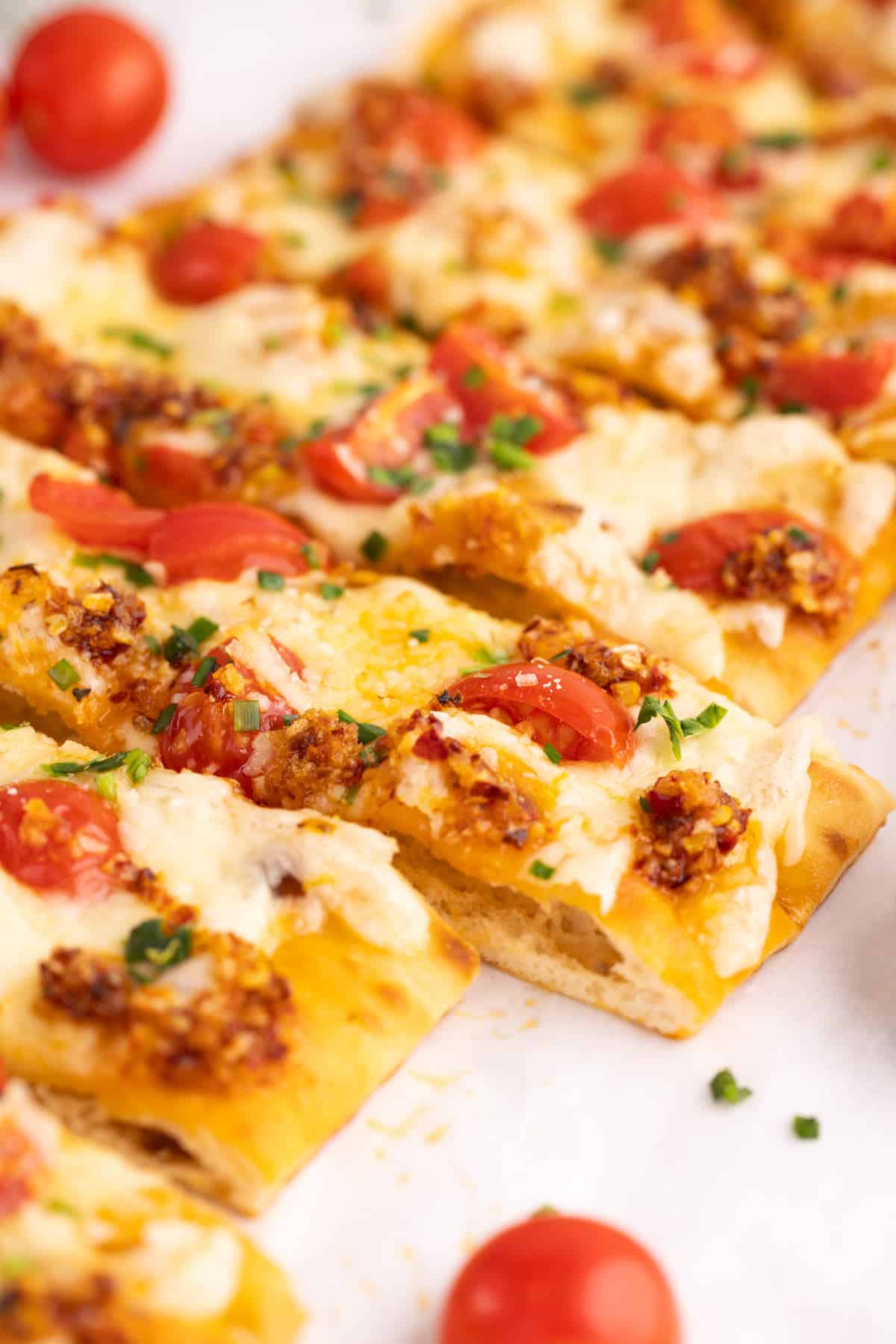 Closeup of flatbread pizza sliced into strips.