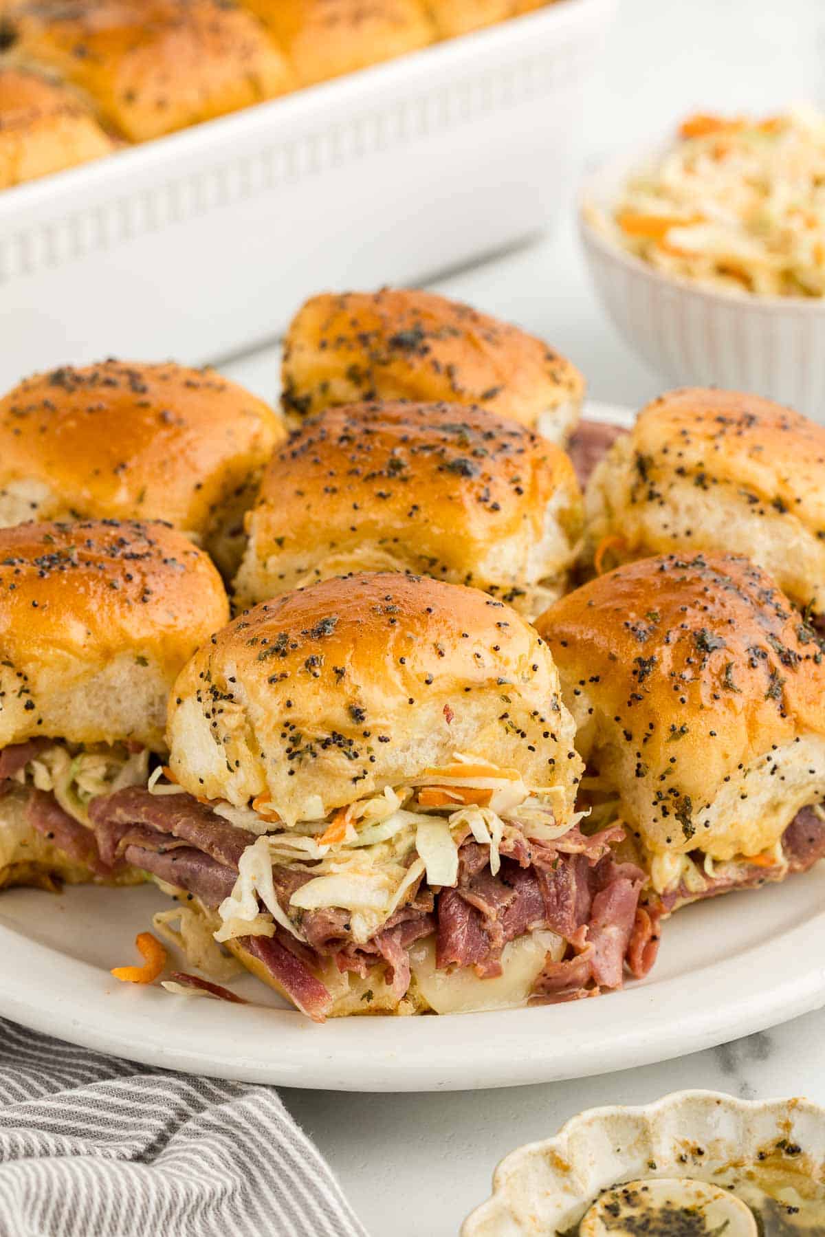 A white platter of pastrami sliders.