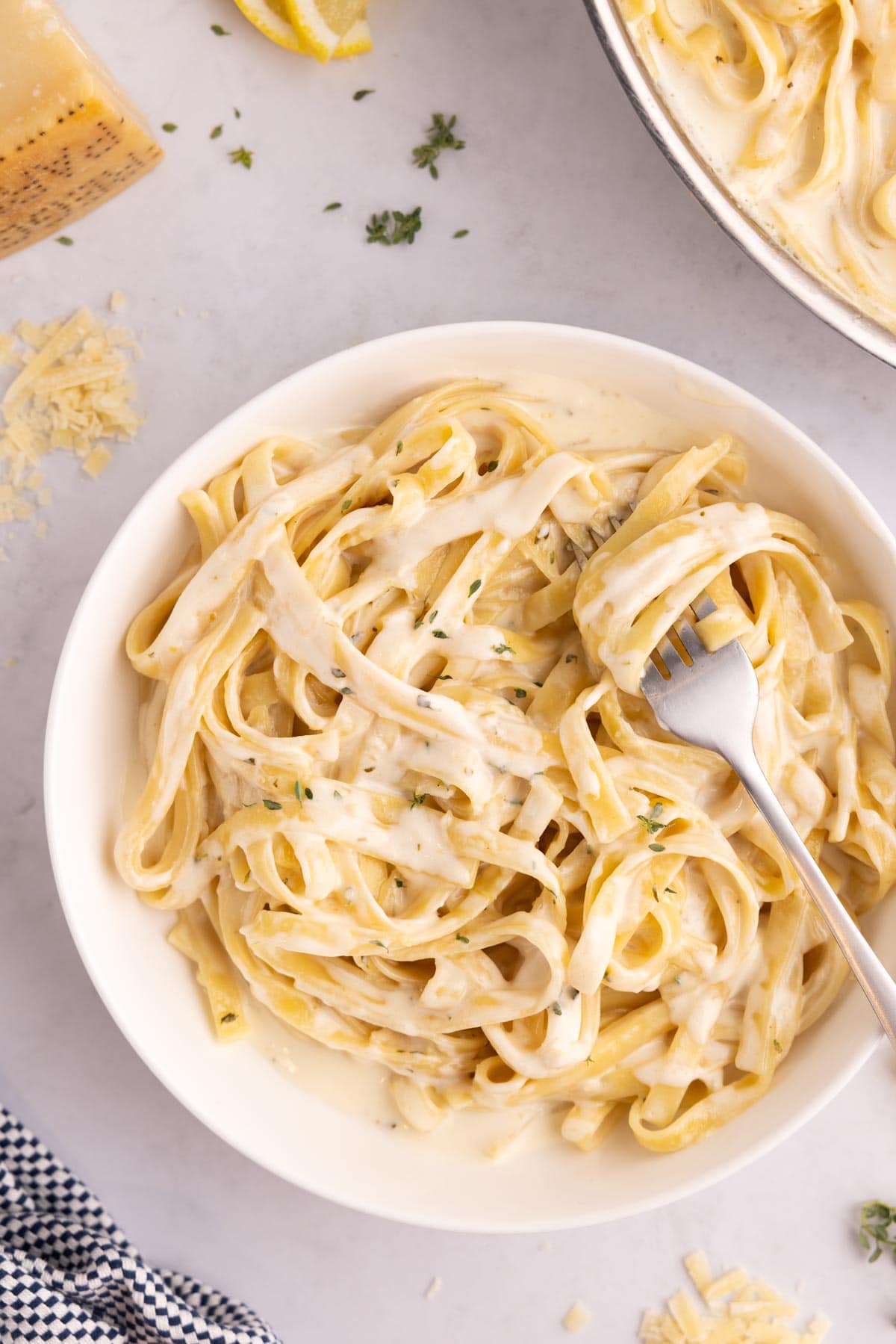 A bowl of lemon alfredo with w fork twisted into it.