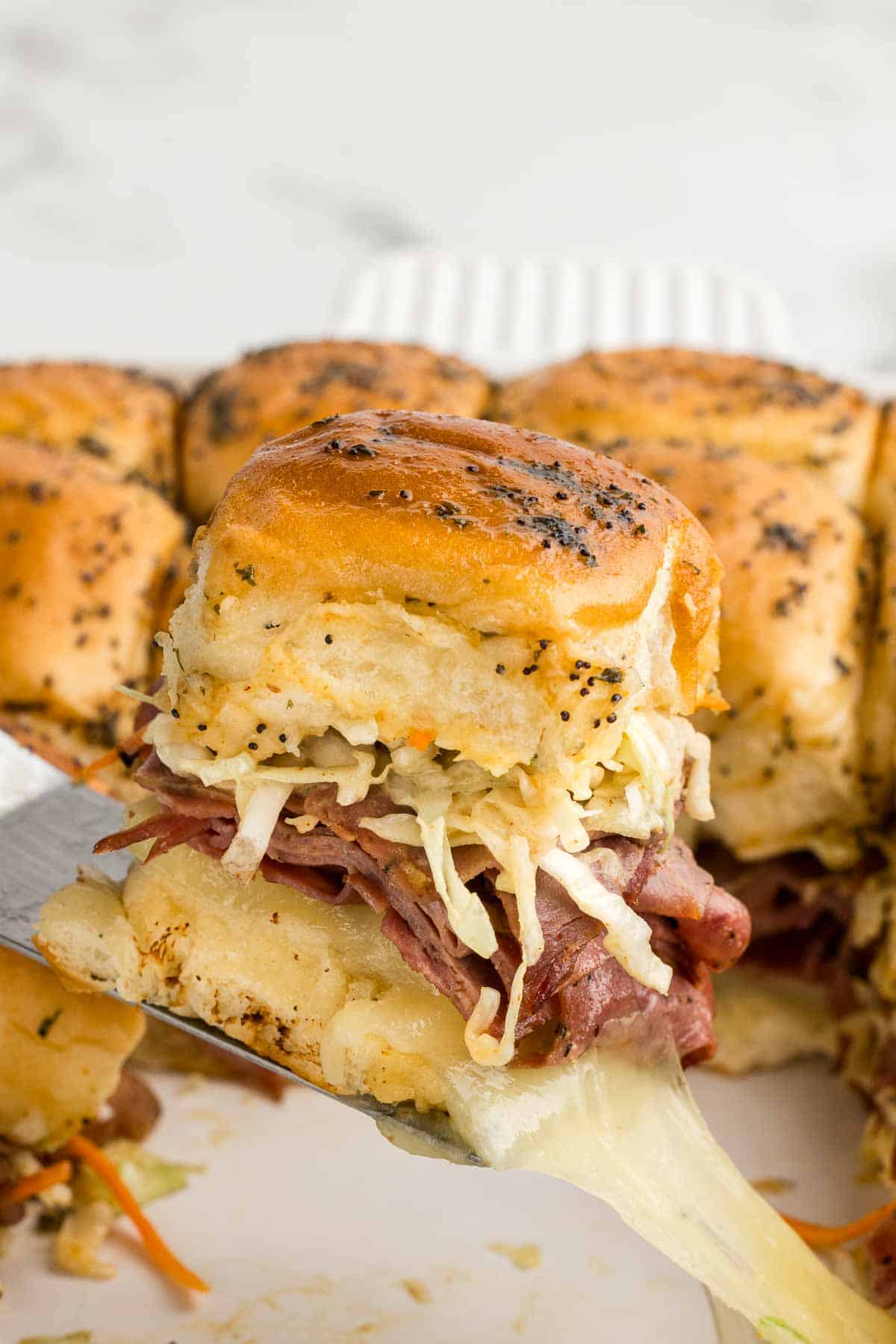 A slider perched on a spatula over a glass baking pan.