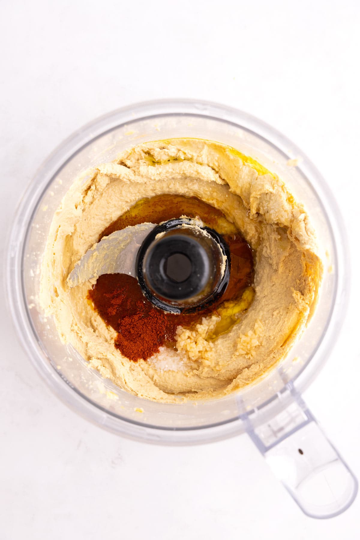 Spices added to blended hummus in a food processor.