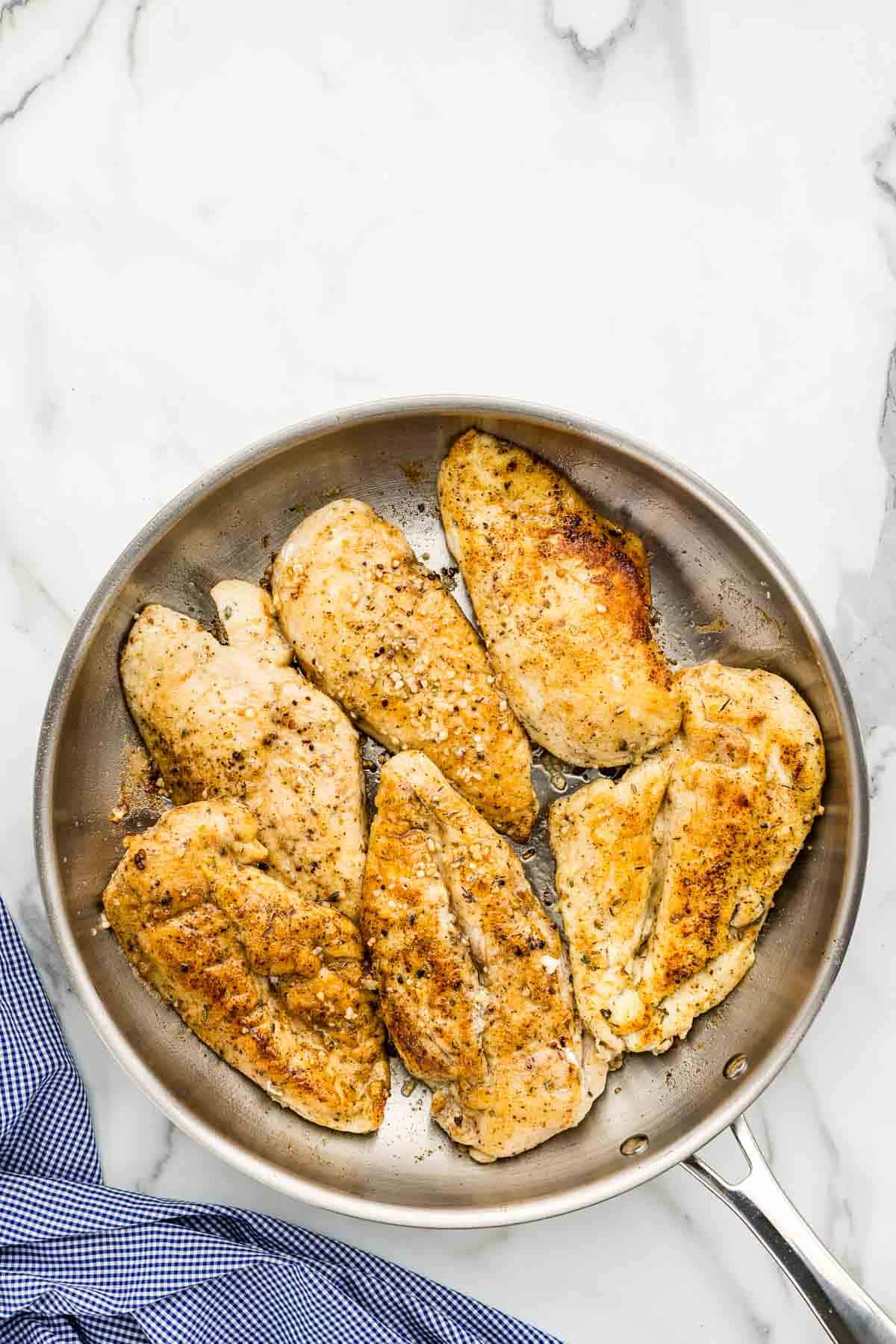 Seasoned lemon chicken in a cooking pan.