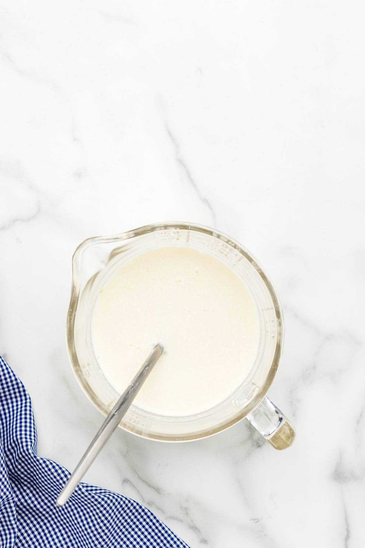 Chicken sauce getting stirred in a glass measuring cup with a small whisk.