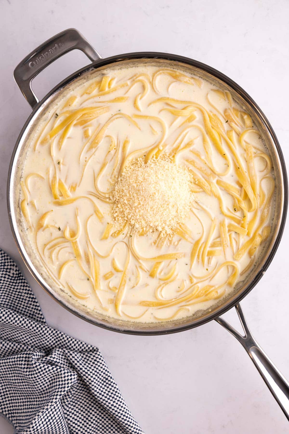 Parmesan added to a pot of alfredo.