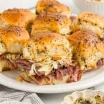 Hawaiian roll pastrami sliders gathered on a white serving platter.