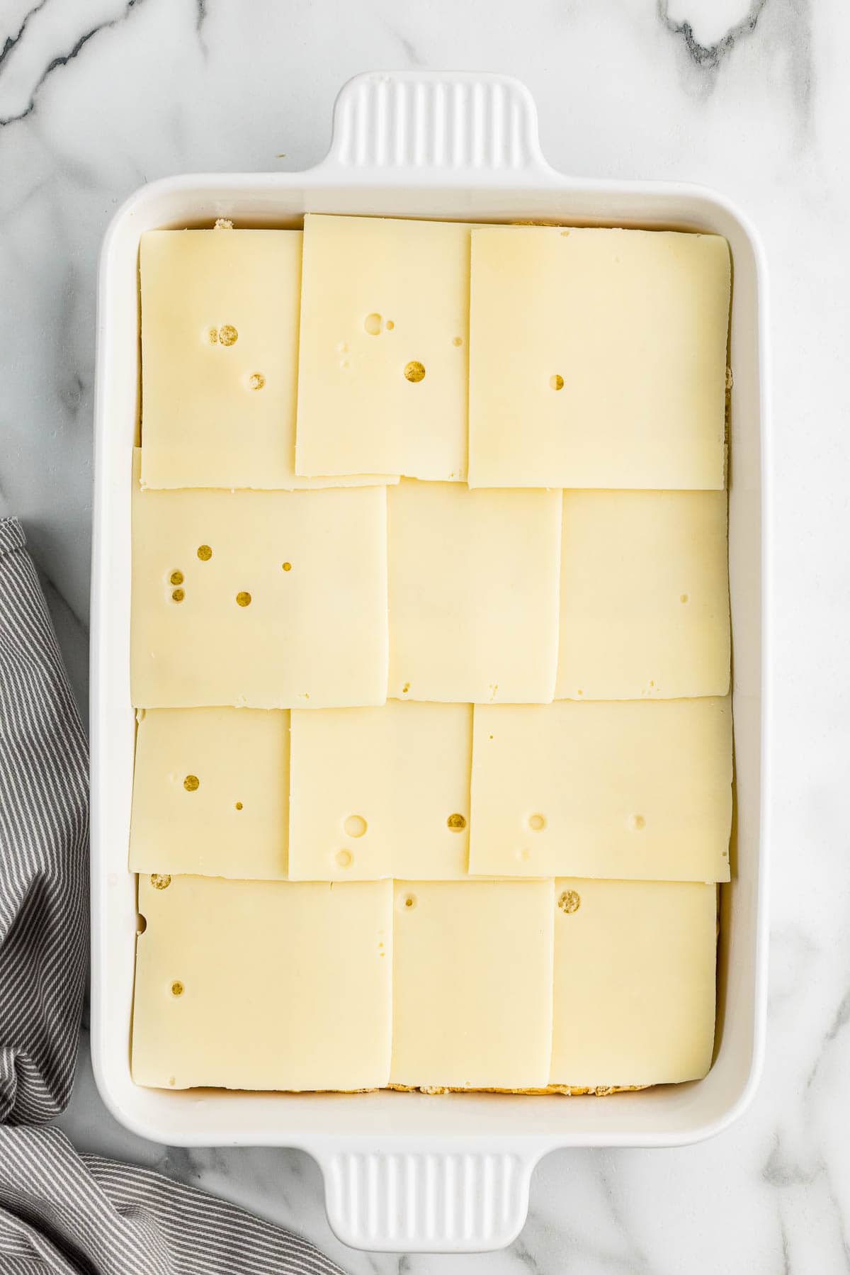 A baking pan with bread and cheese layered in it.