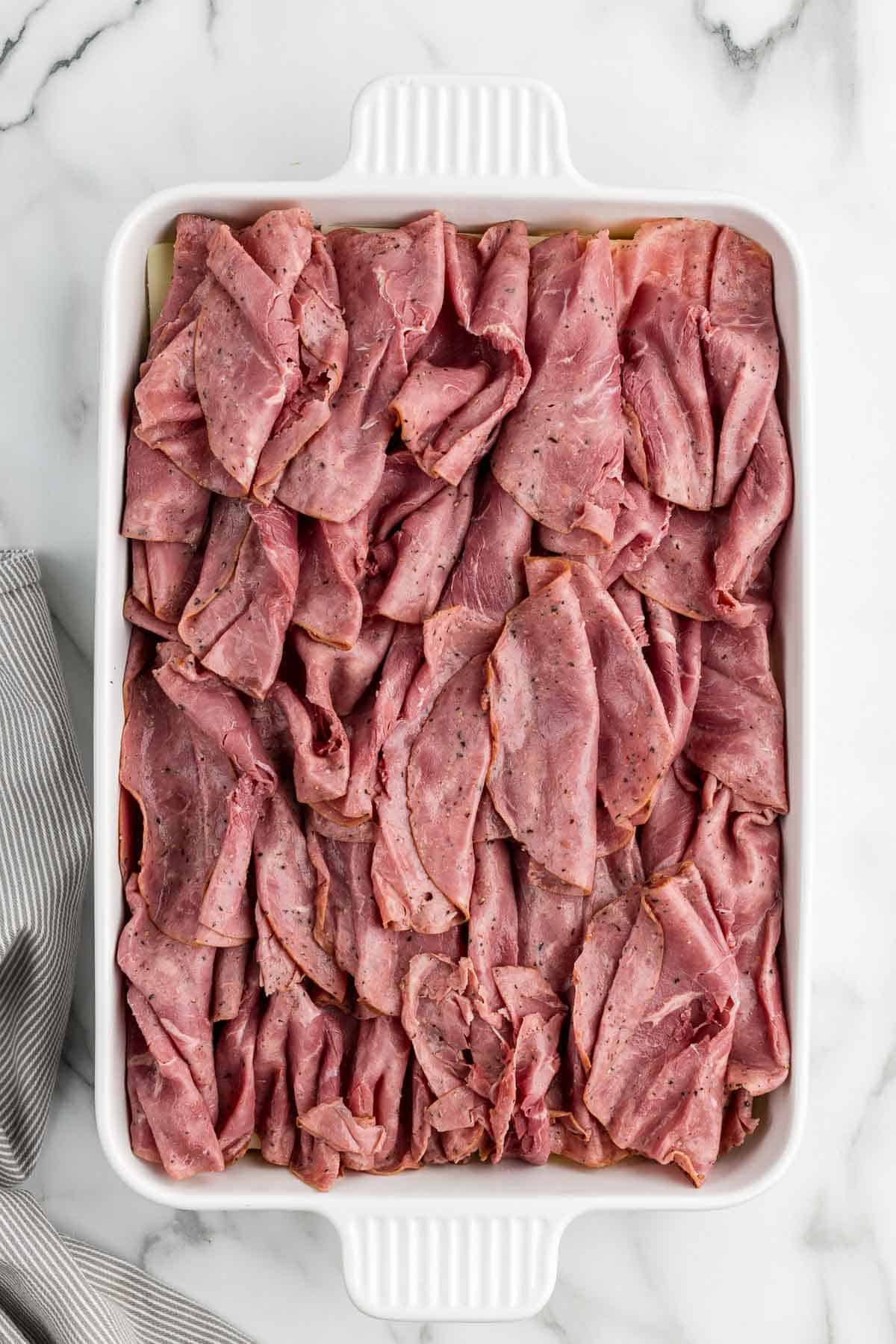 Pastrami laid on top in a baking pan.