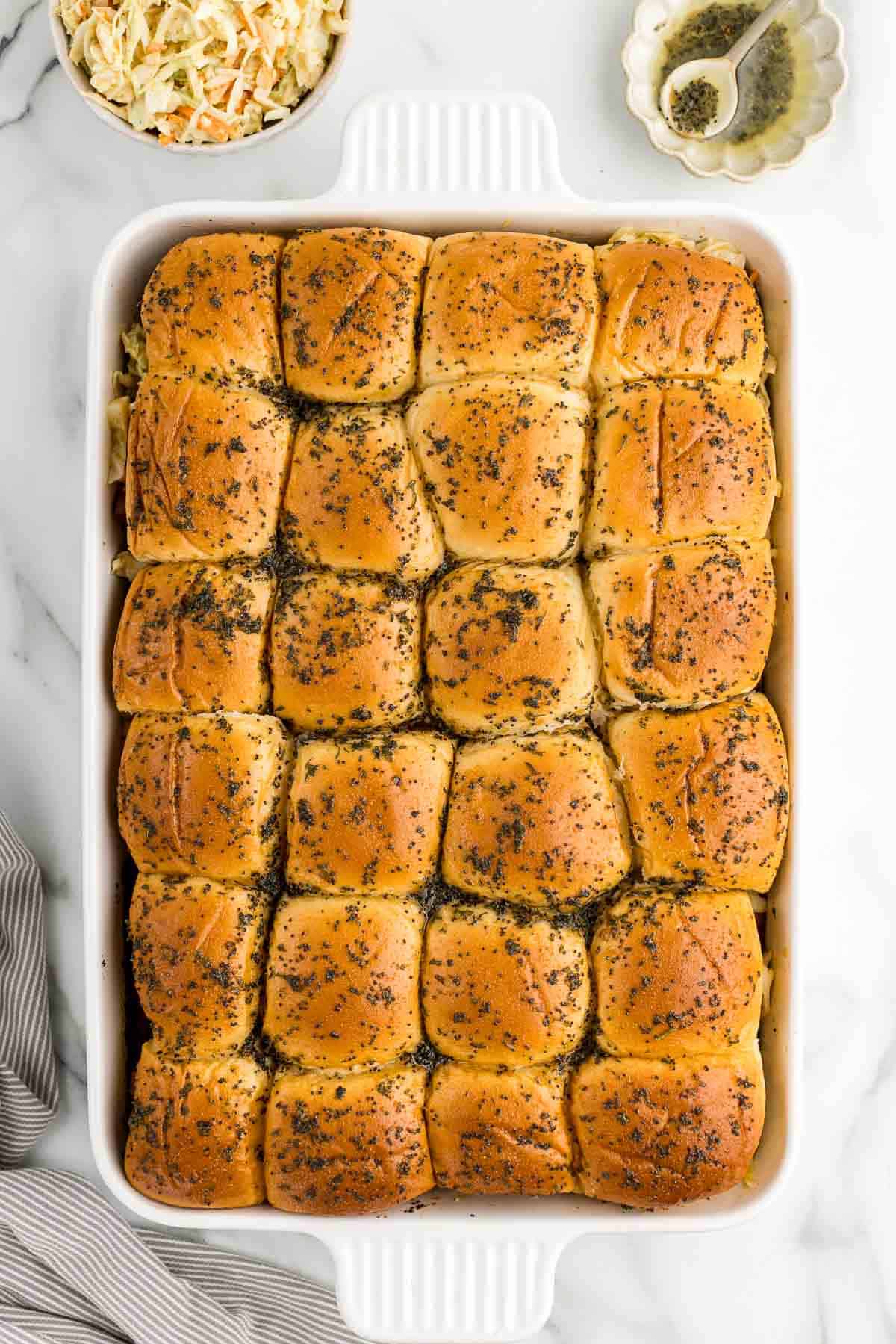 Baked sliders with pastrami in a glass white pan.