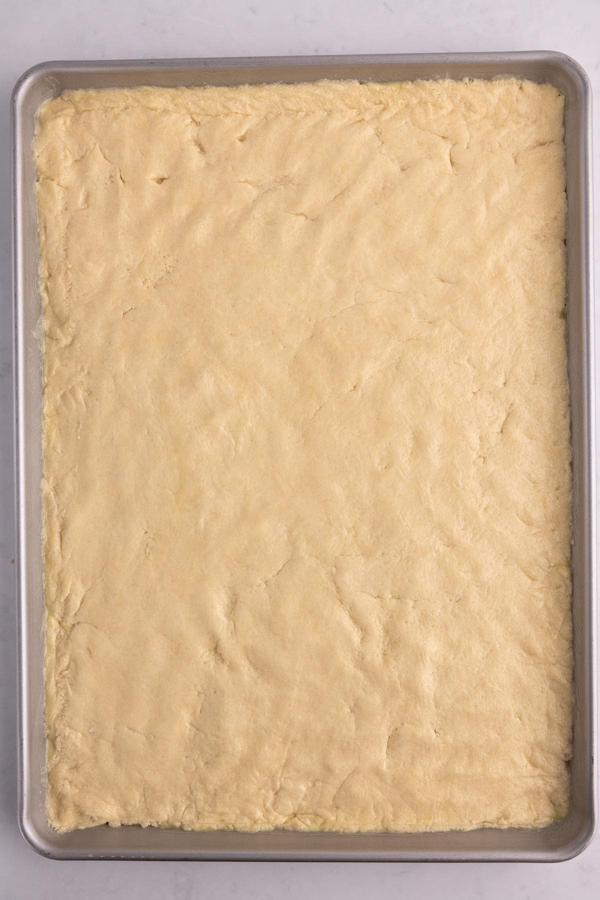 Cookie dough pressed flat into a sheet pan.
