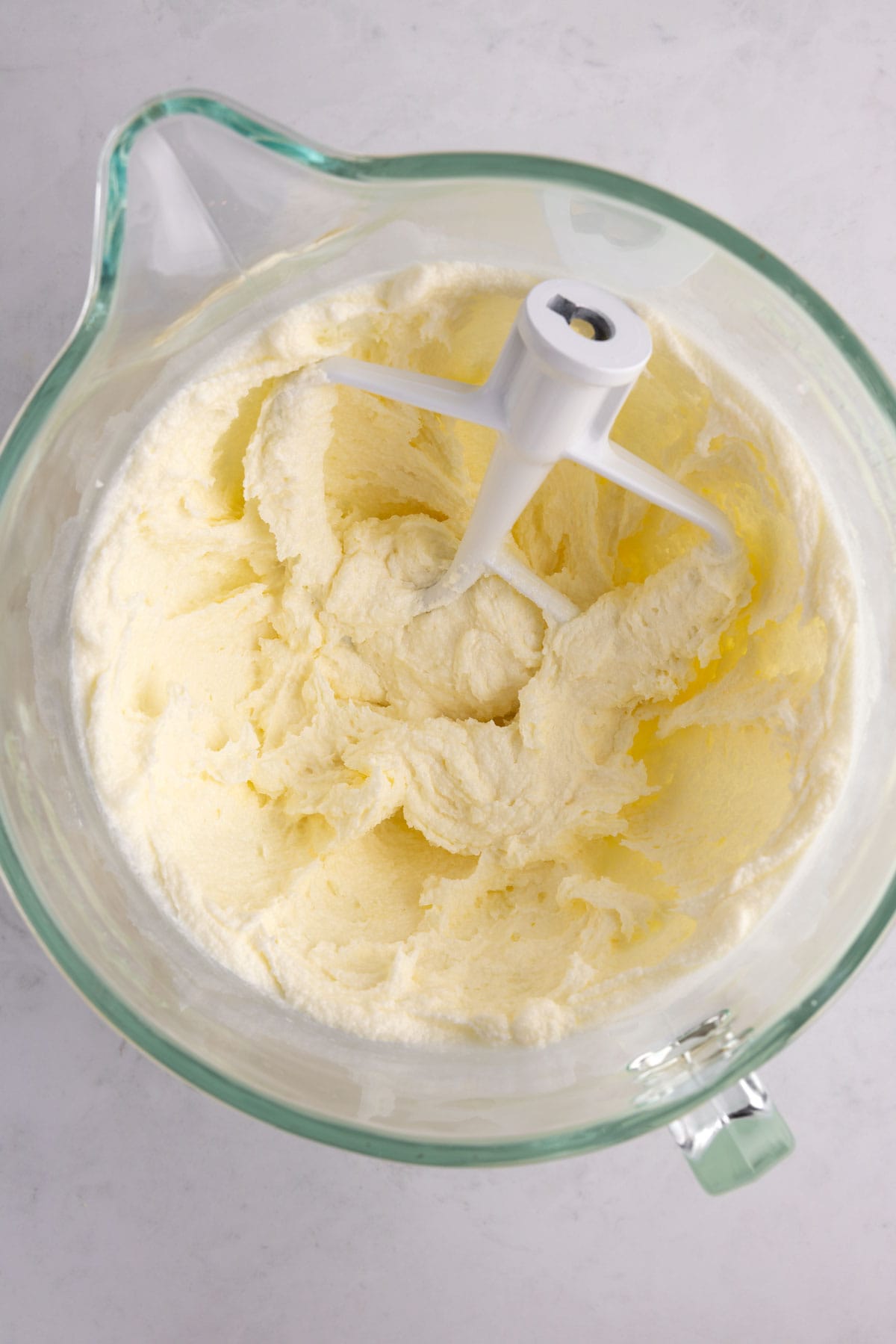 Blended sugar cookie dough ingredients in a glass mixing bowl.