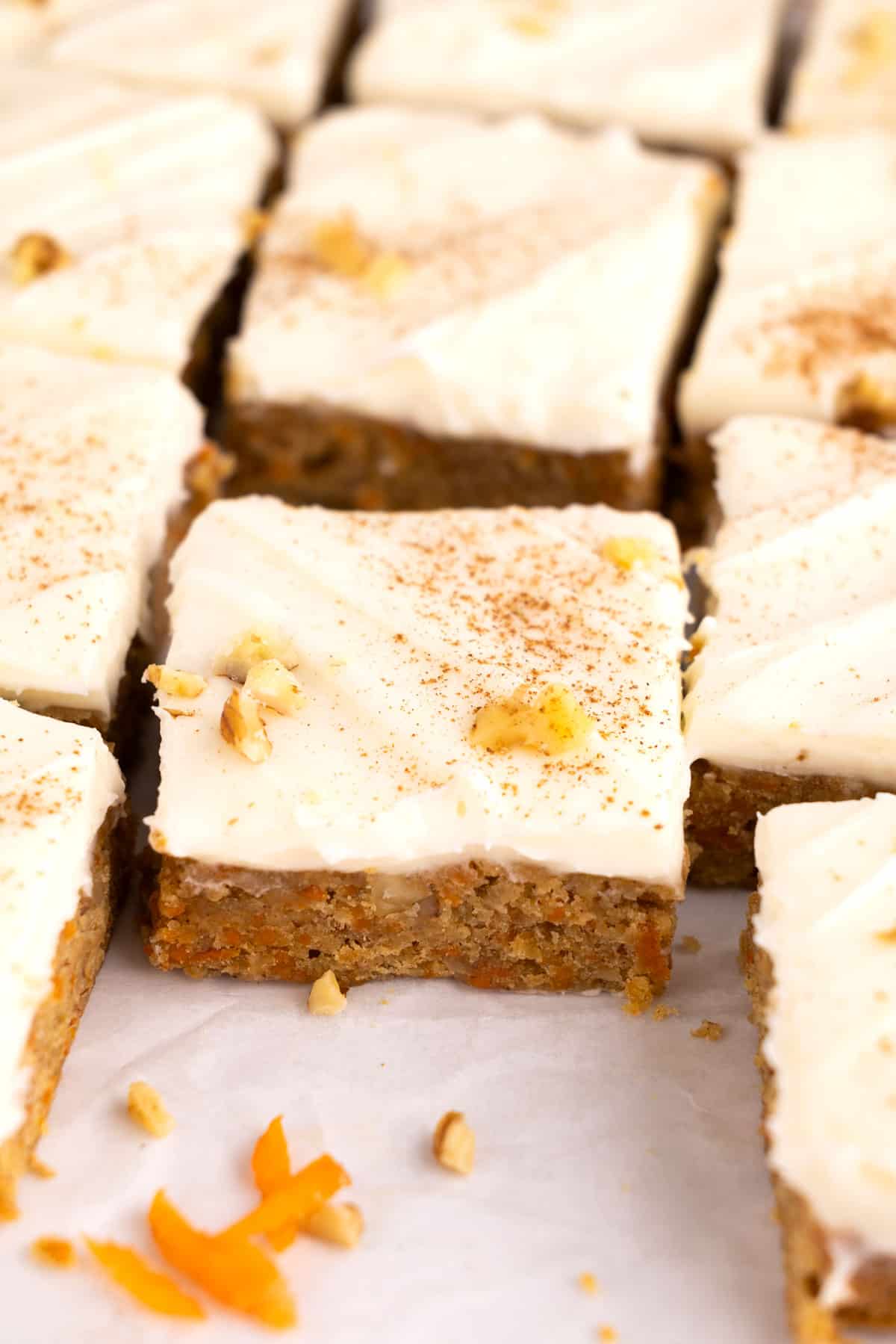 Rows of carrot cake bars on parchment paper.