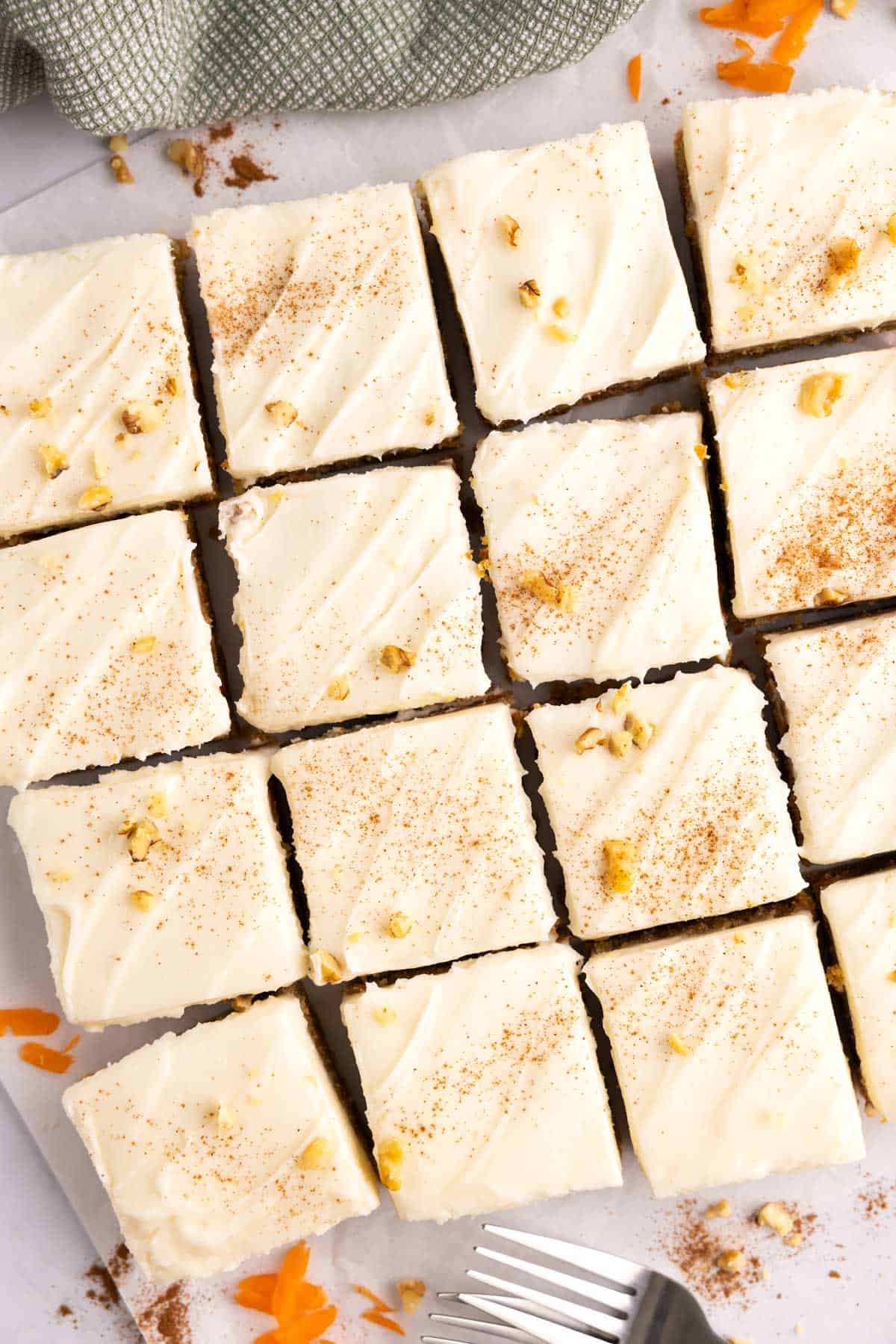 Overhead of carrot cake cut into bars with a pile of forks beside them.