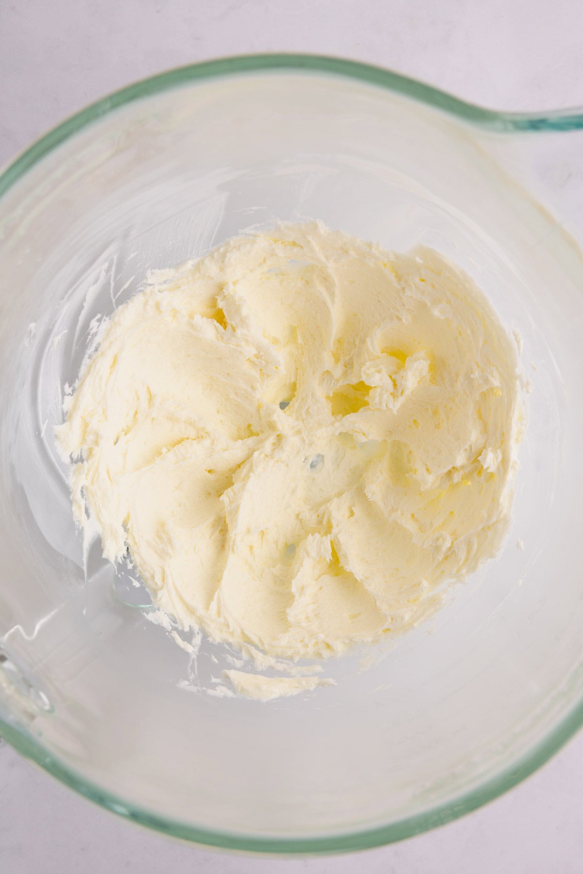 A glass measuring cup of cream cheese frosting.