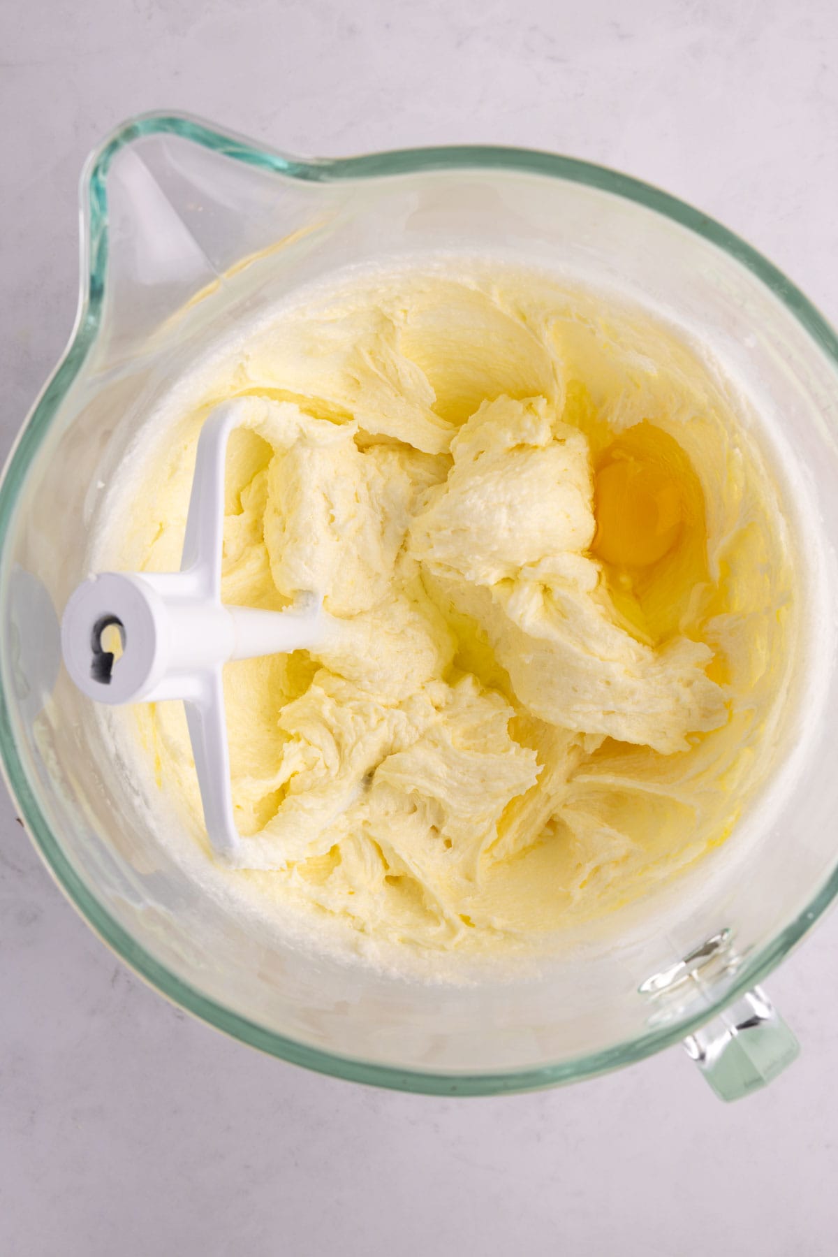 Eggs added to a bowl with a blending paddle.