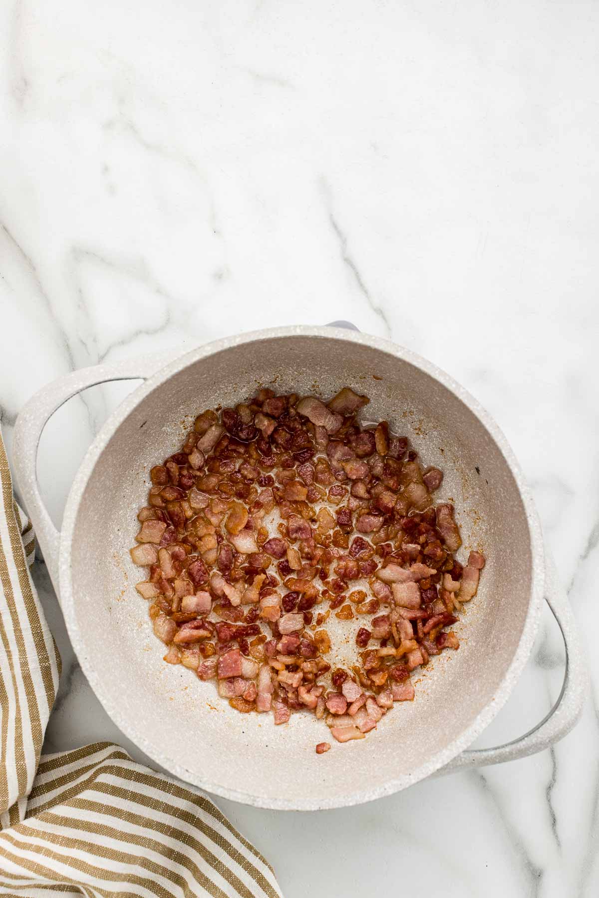 Chopped bacon being cooked in a pot.