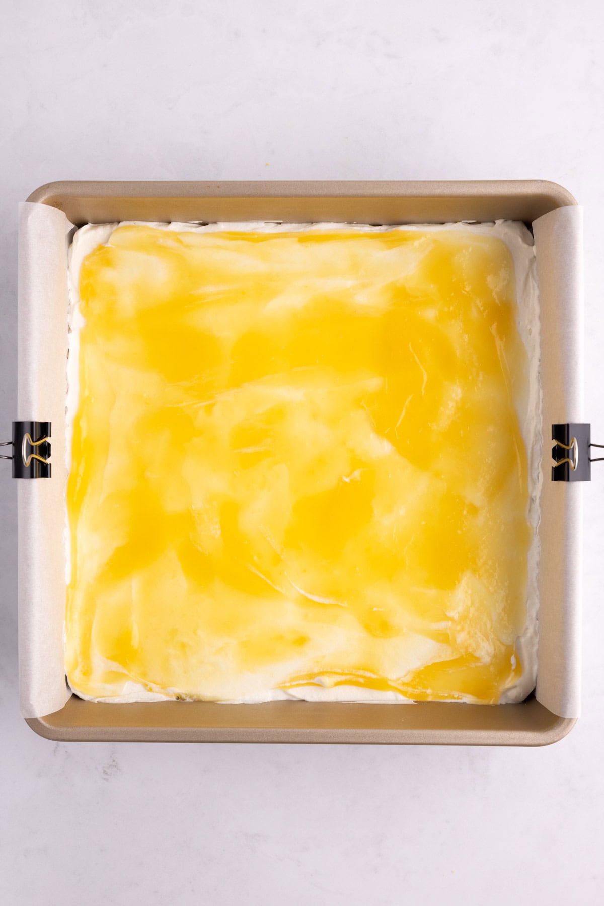 Lemon curd added to a baking pan of shortbread cookies and filling.