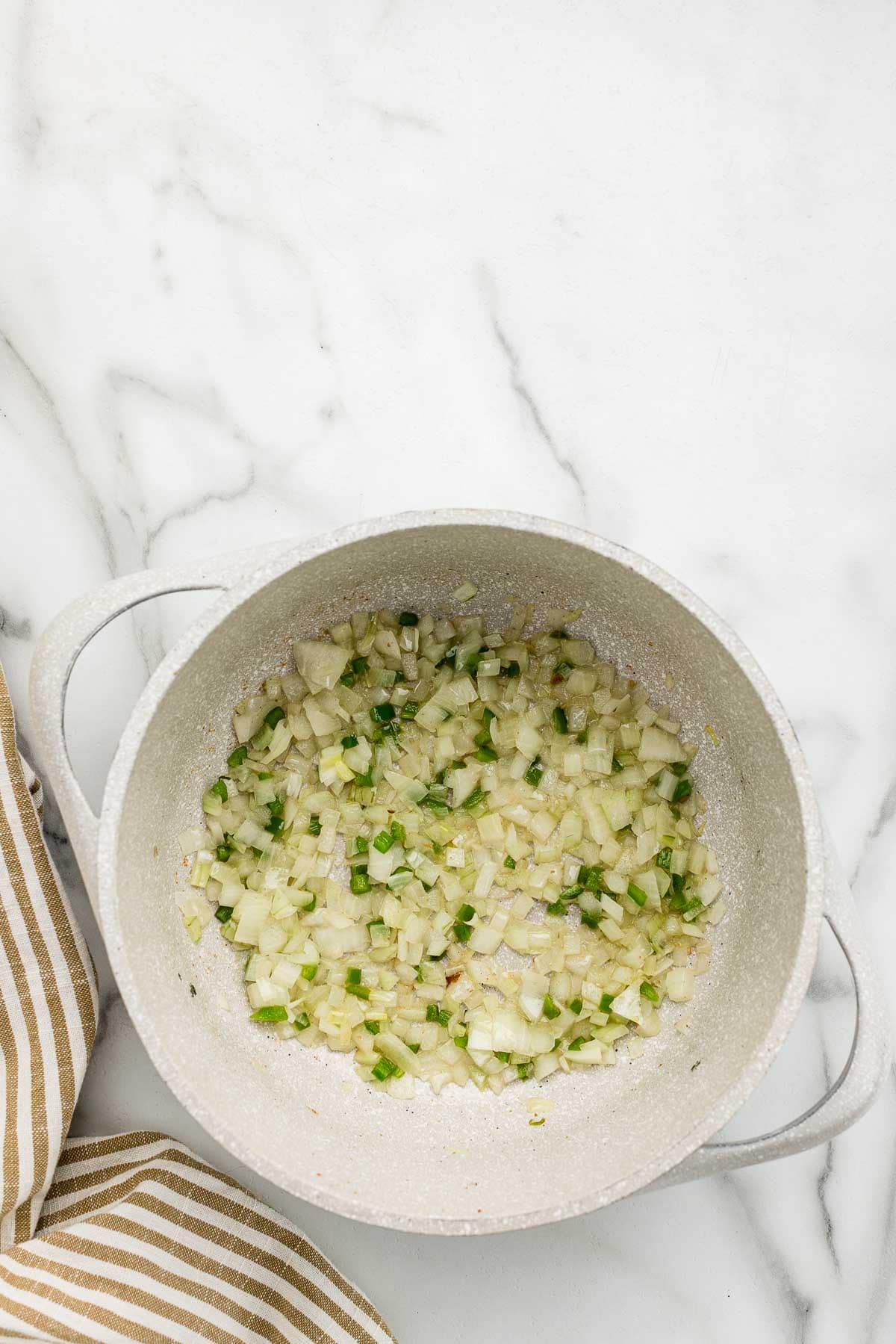 Mixed onions, garlic, and jalapenos at the bottom of a pot.