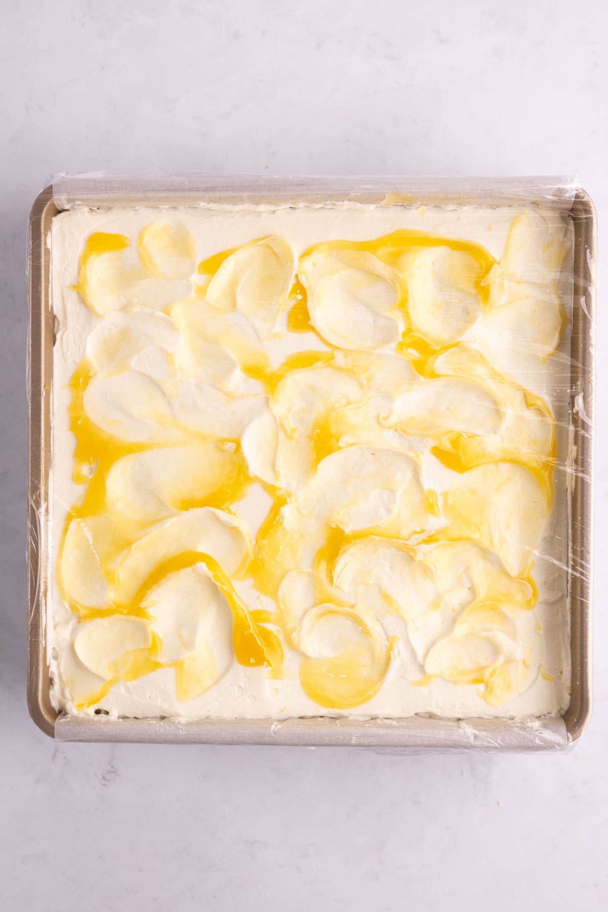 Assembled lemon icebox cake covered with plastic wrap.