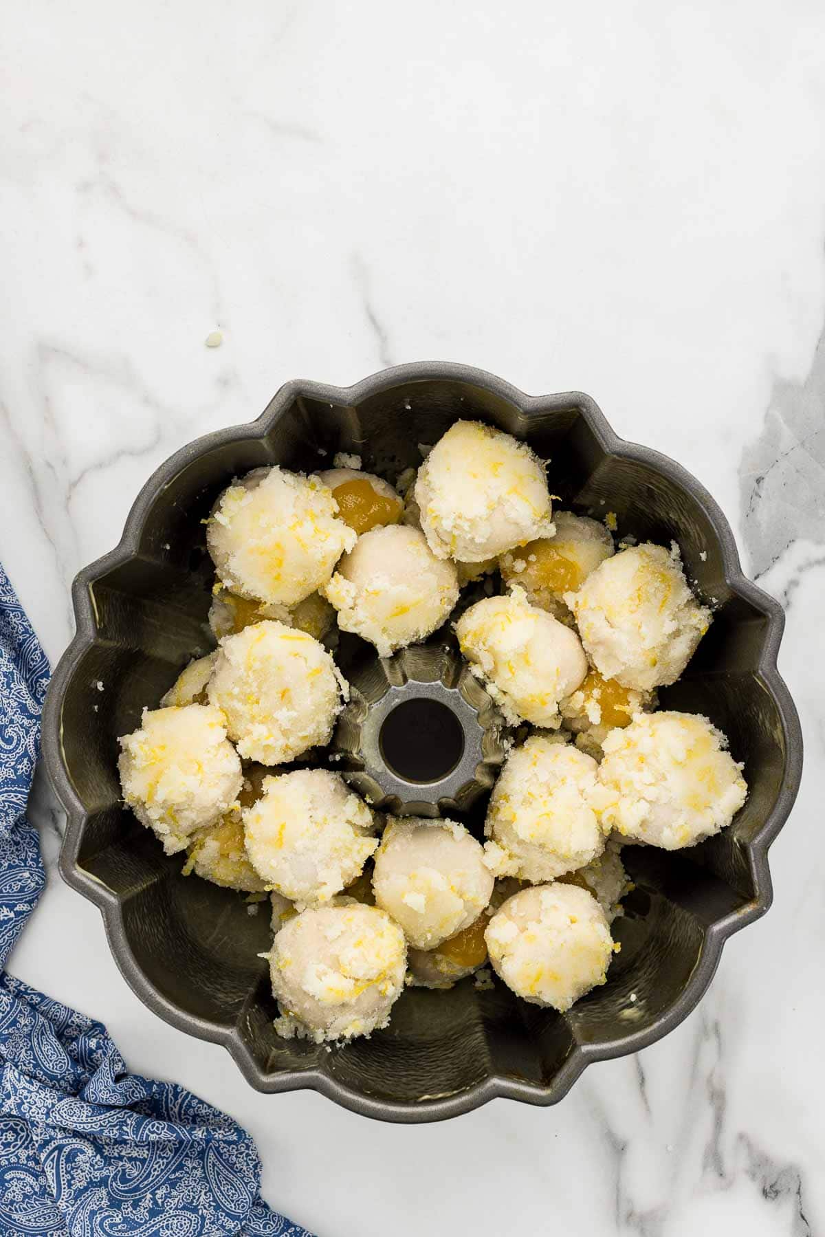 Two rows of dough balls stacked on top of each other in a baking pan for bundt cakes.