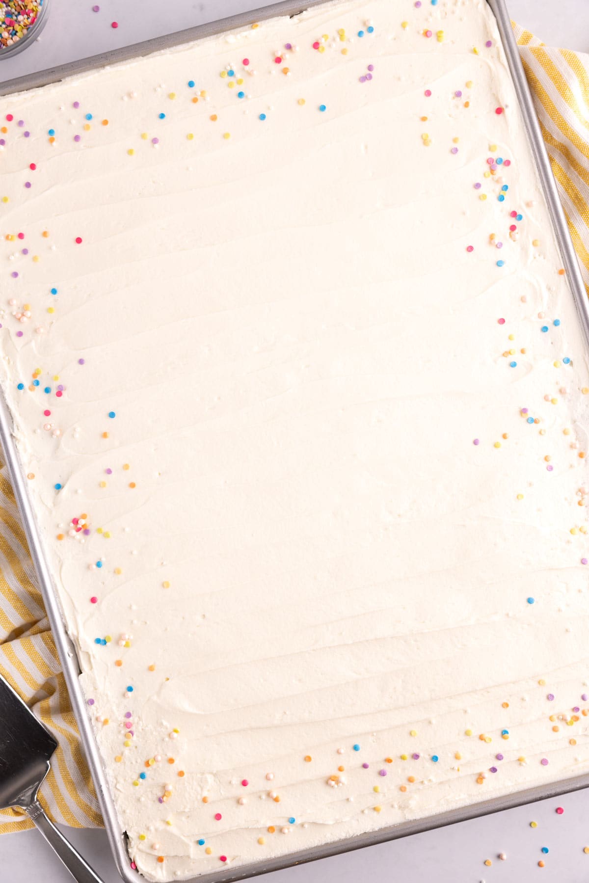 A large pan of sugar cookie bars with sprinkles and frosting.