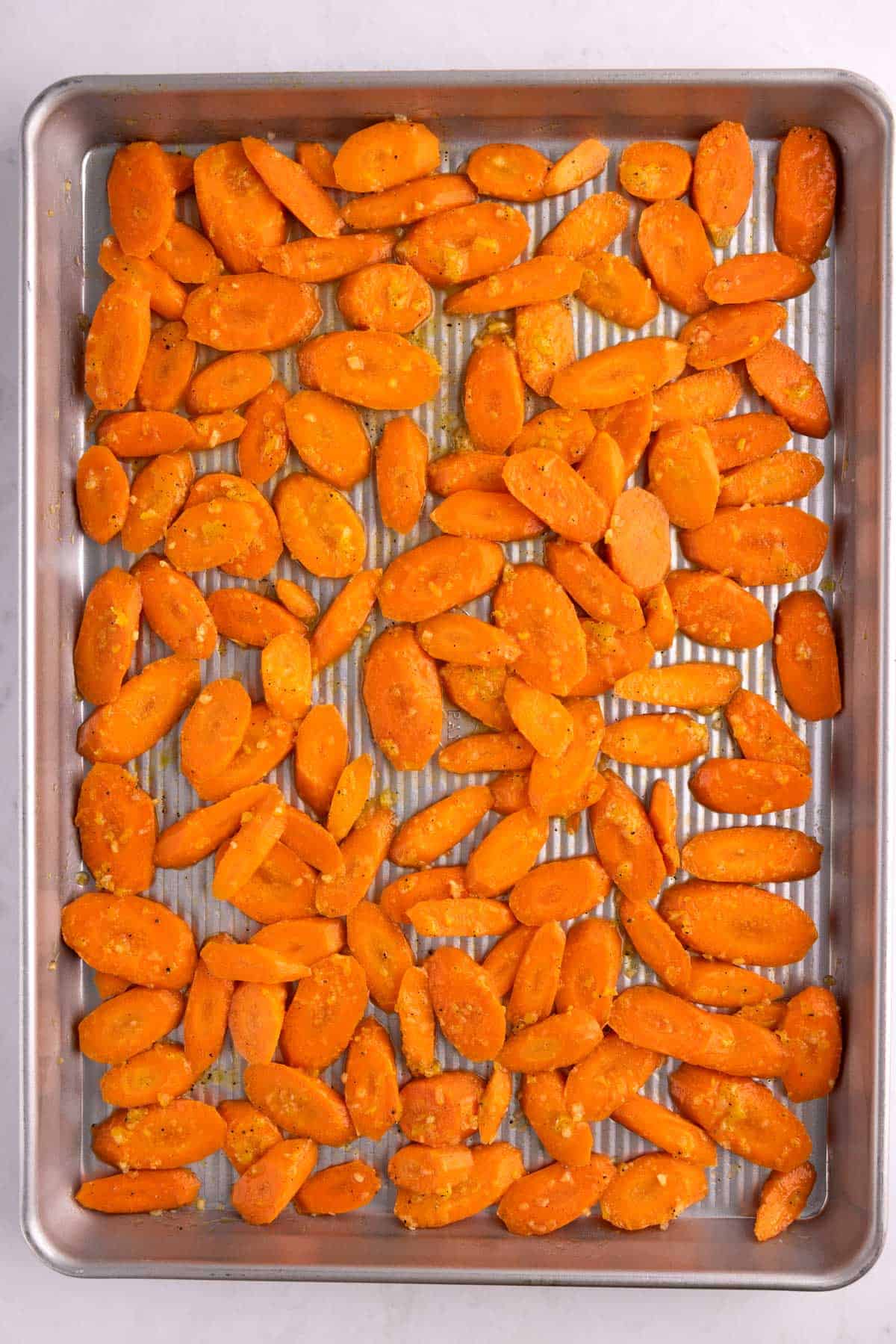 Coated carrot slices on a sheet pan.