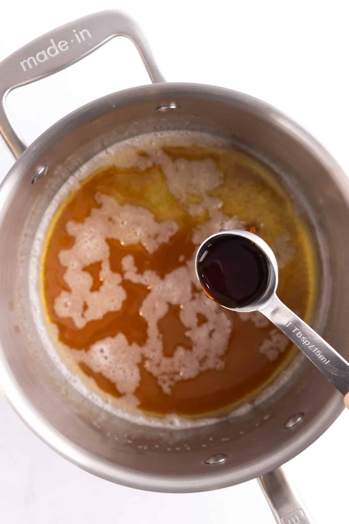 Vanilla being poured into a saucepan full of toasted butter.