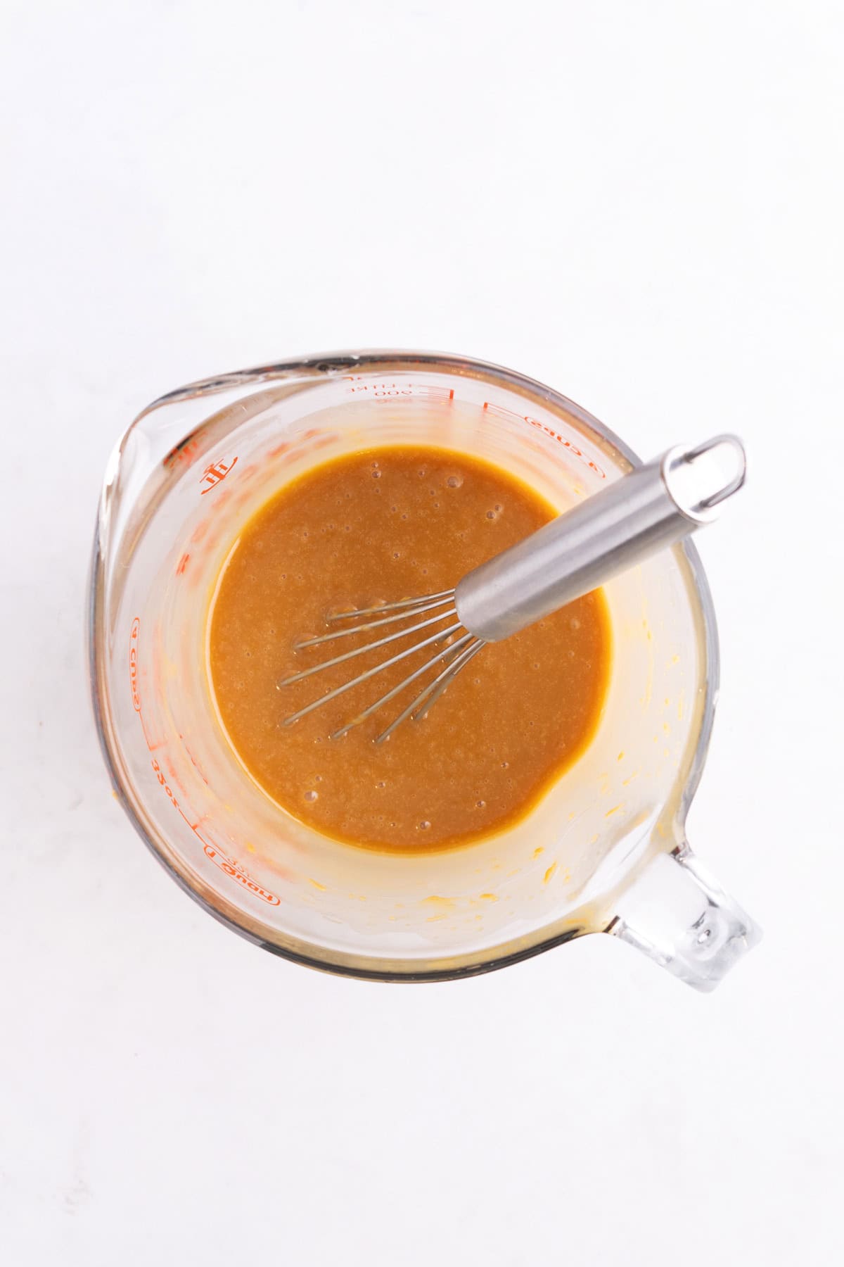 Caramel sauce in a mixing dish with a whisk.