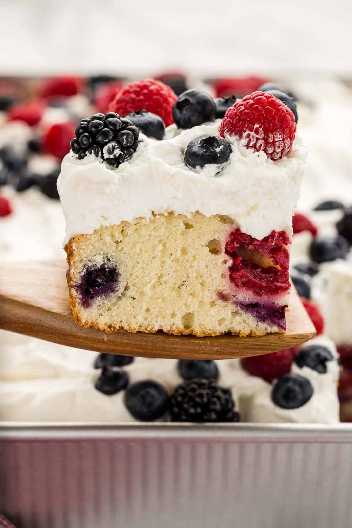 A wooden spatula holding a slice of berry cake.