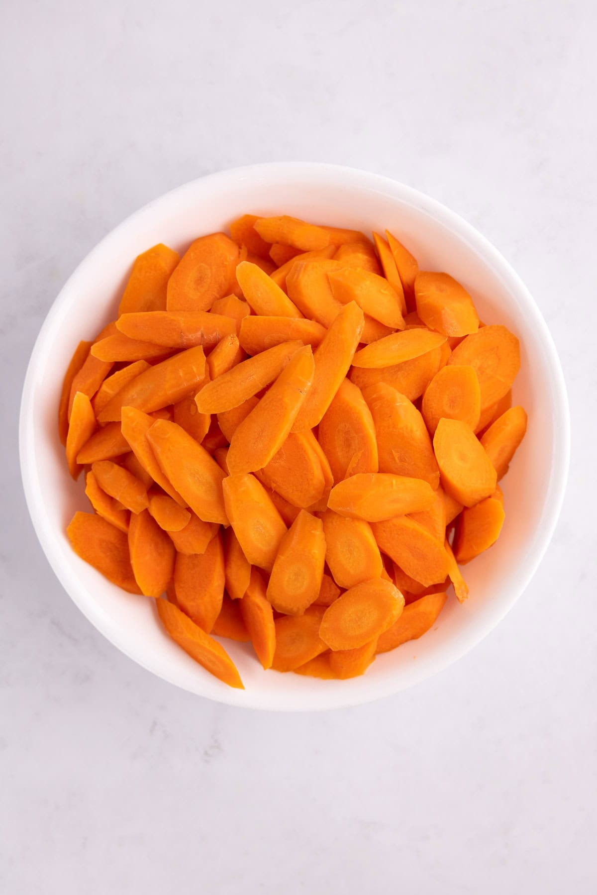 Raw carrot sliced in a white bowl.