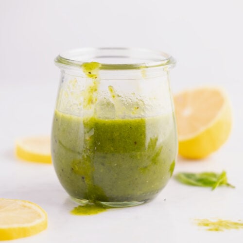 A jar of lemon basil vinaigrette with a trail of dressing dripping down the outside.