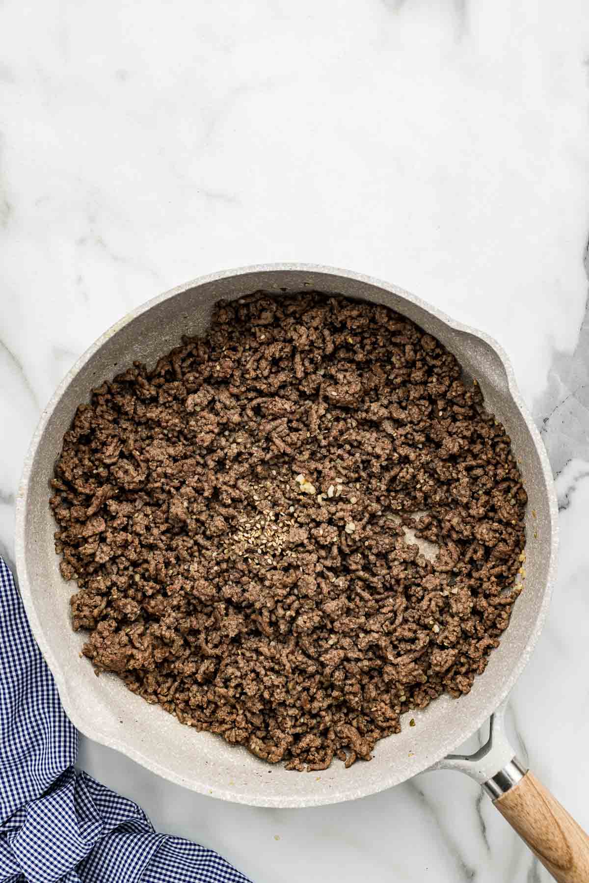 Seasonings added to a skillet of cooked ground beef.
