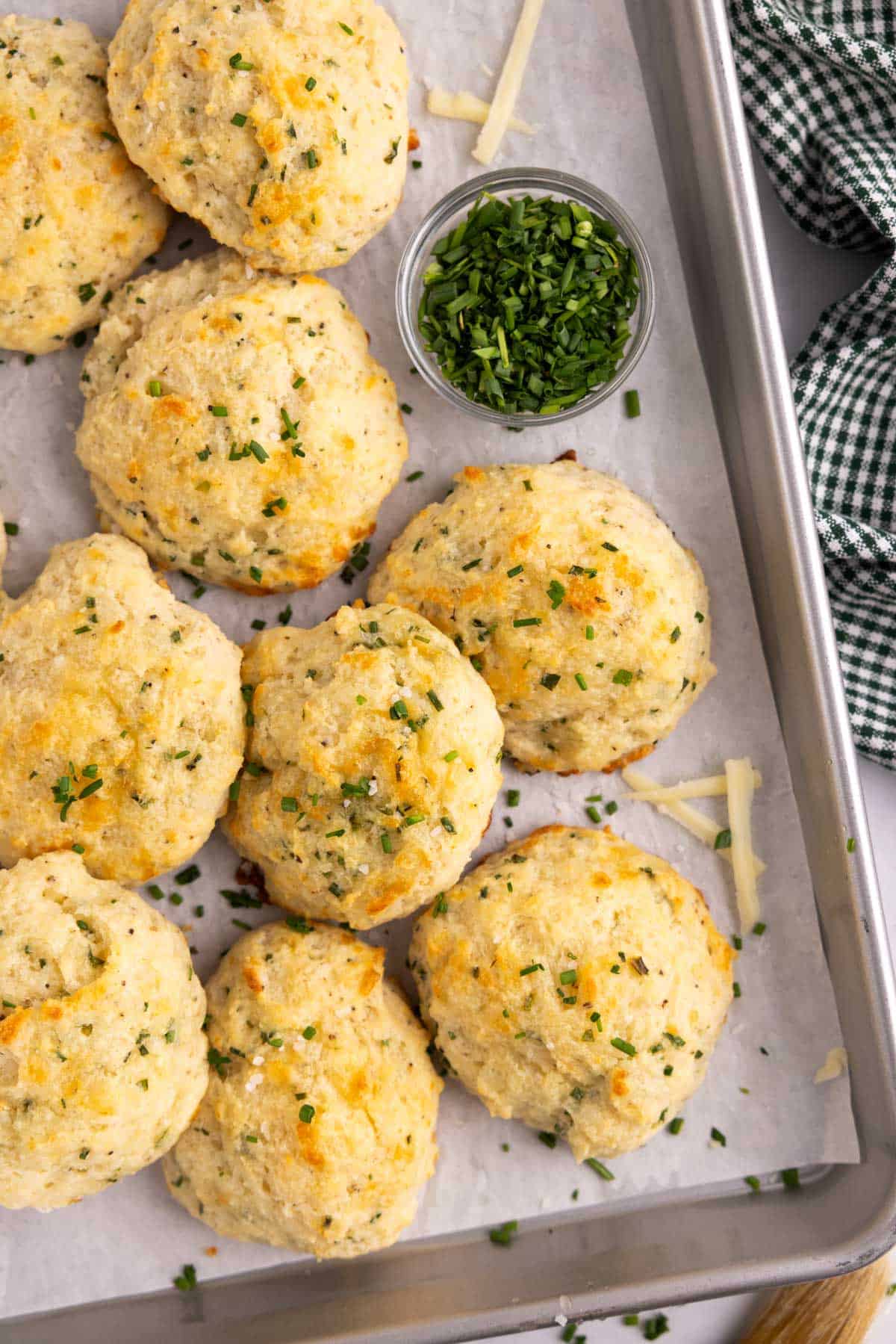 A tray of cheddar chive biscuits with a small dish of chives beside them.