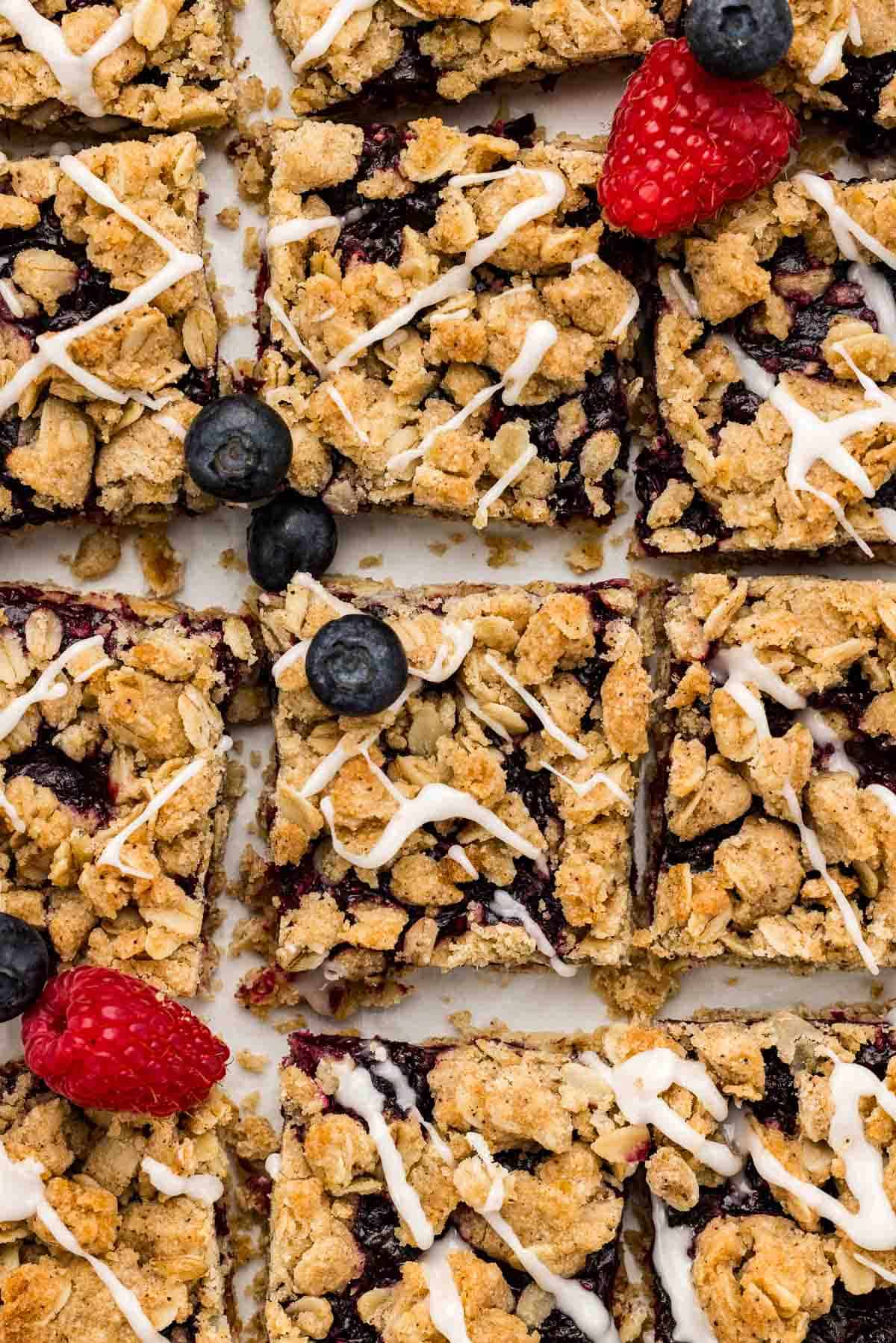 Berry bars spread across parchment topped with fruit and glaze.