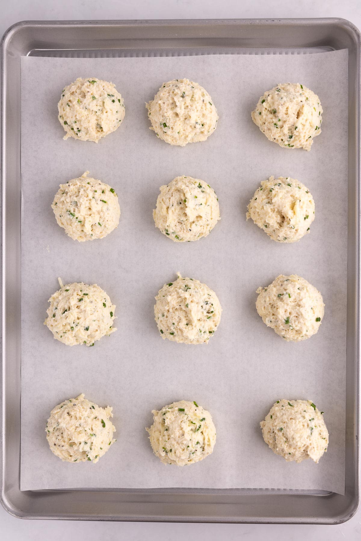 Dough balls sitting in rows on a sheet pan.