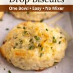 An overlay of text on an image of a cheddar chive biscuit sitting on a baking tray.