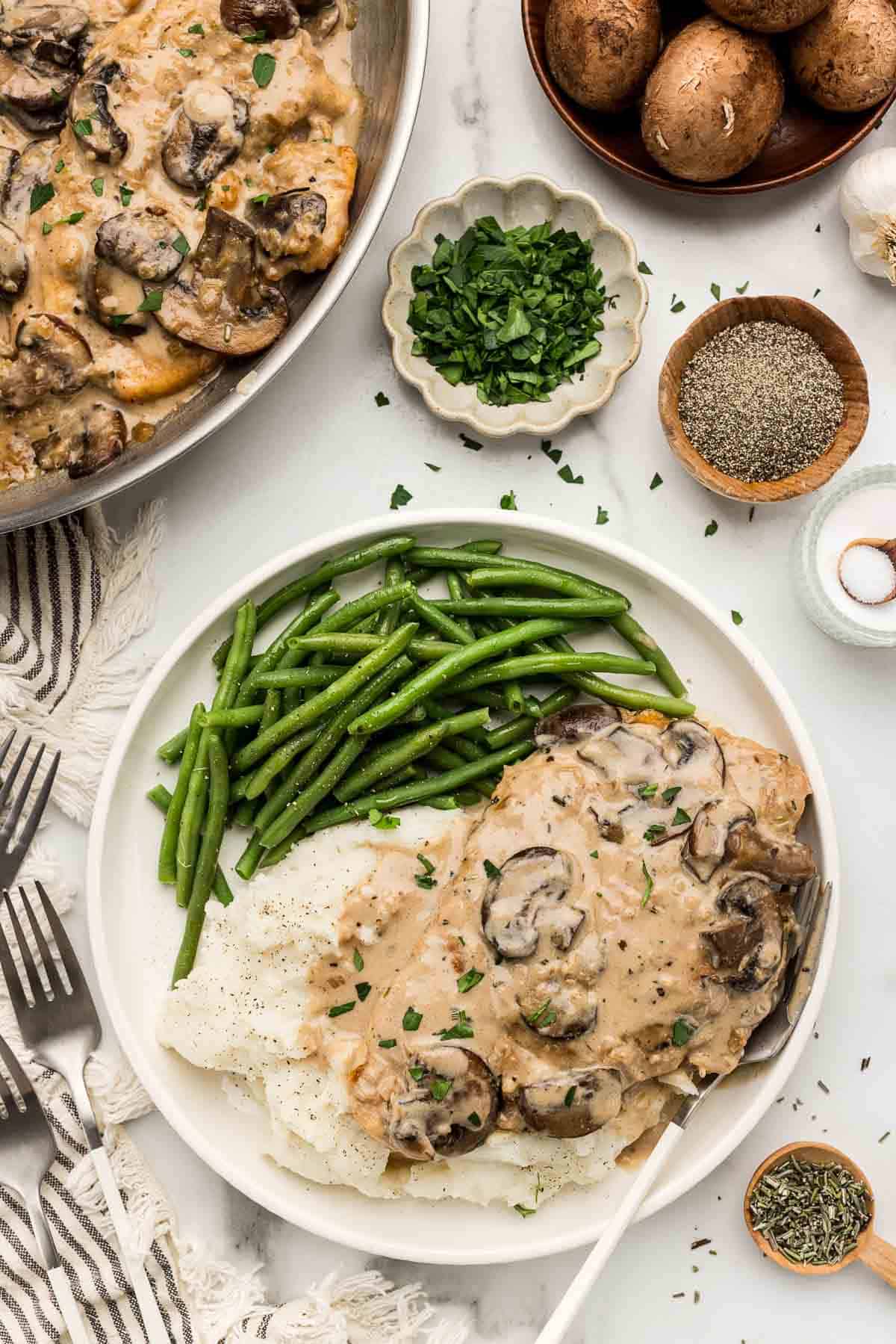 A serving of chicken marsala on mashed potatoes with veggies.