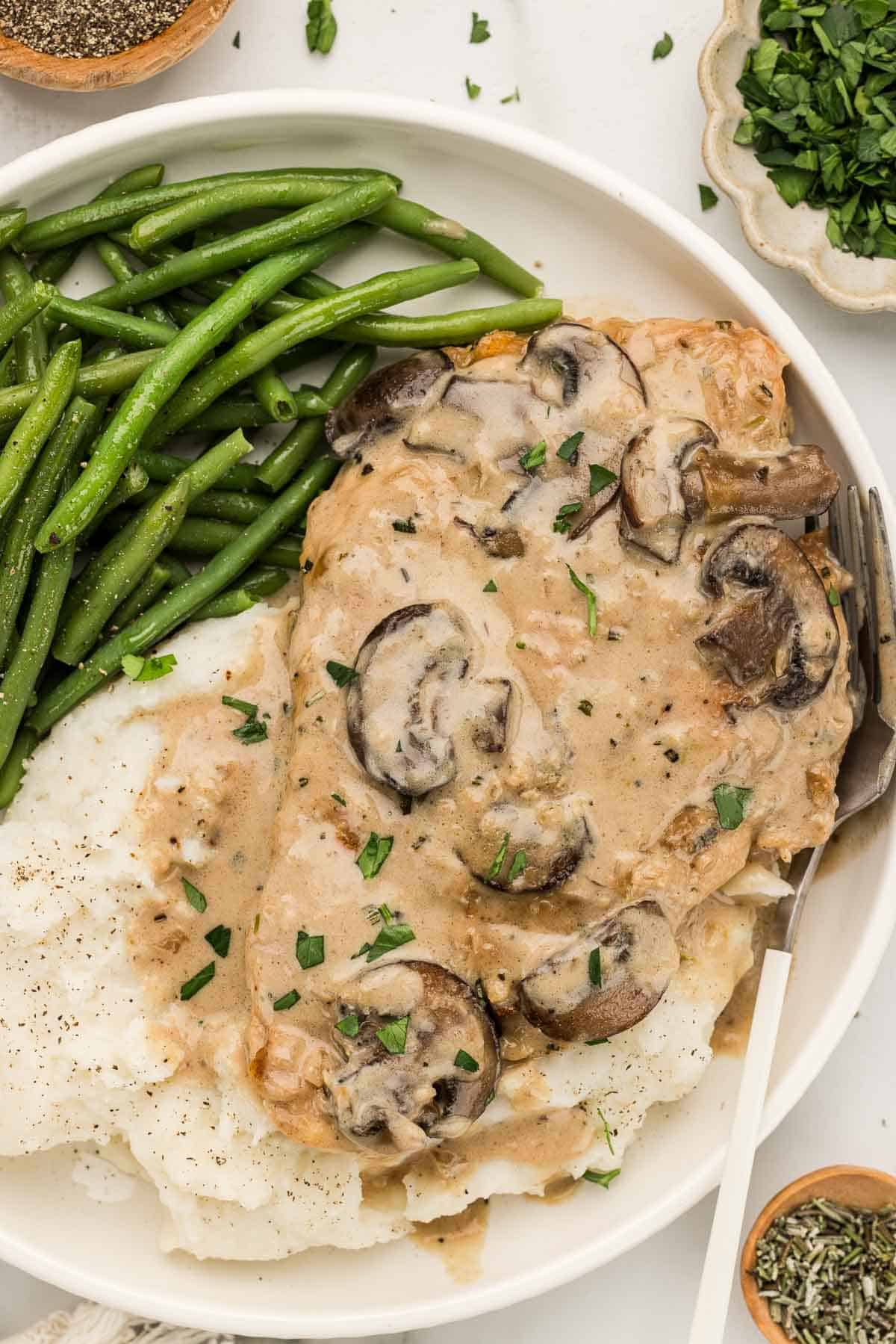 Chicken marsala and potatoes on a white plate with a fork.