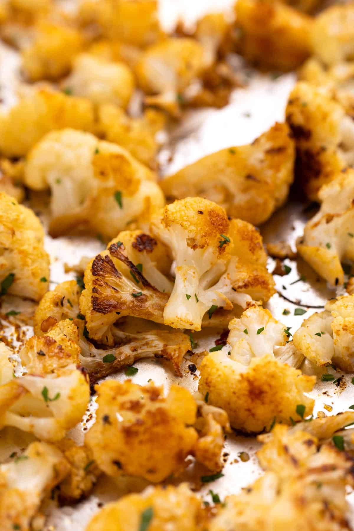 Closeup of a piece of roasted cauliflower on a sheet pan.