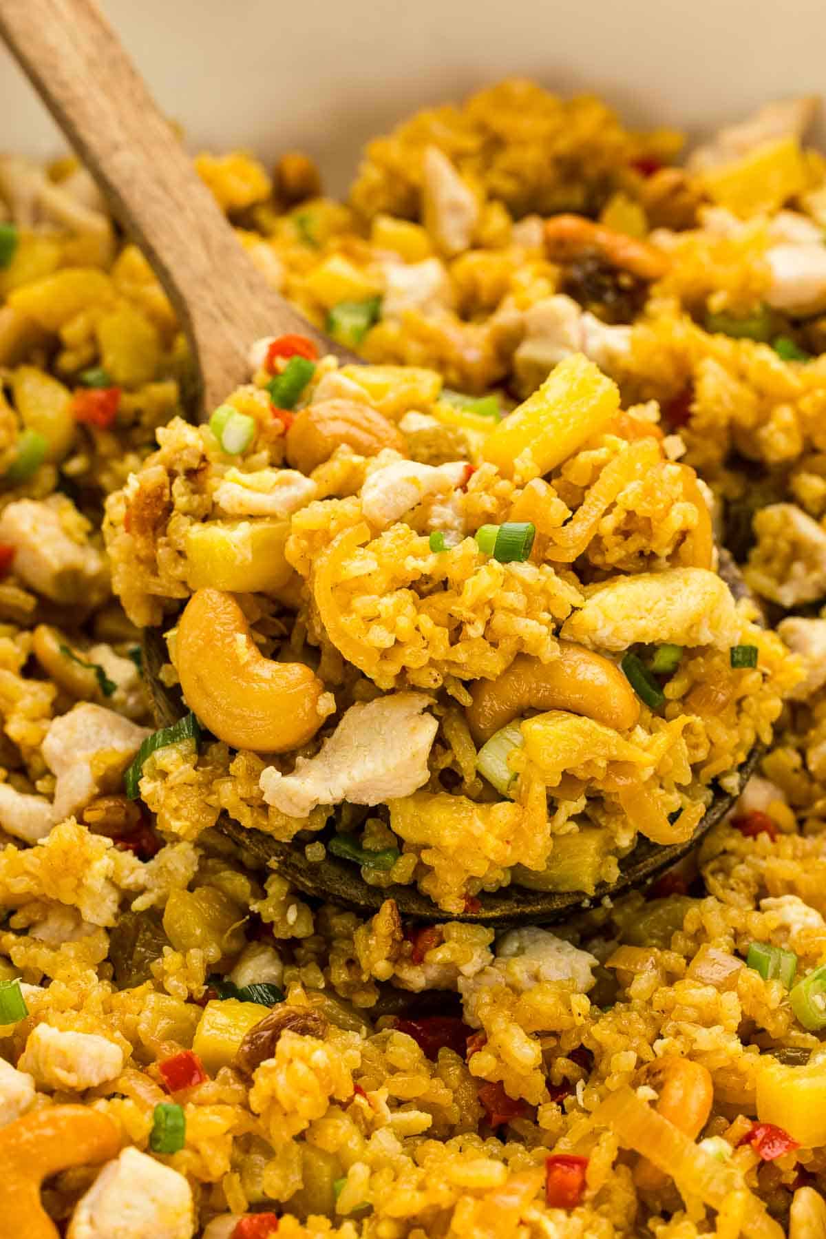 A wooden spoon scooping pineapple fried rice.