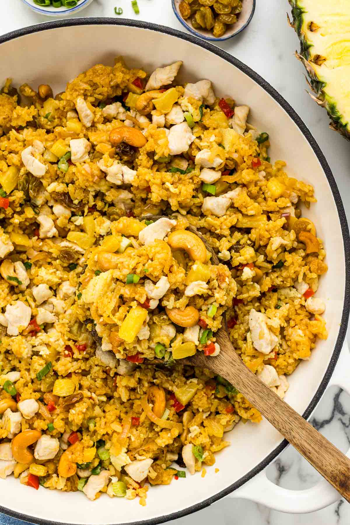 Pineapple fried rice in a skillet with a cooking spoon.
