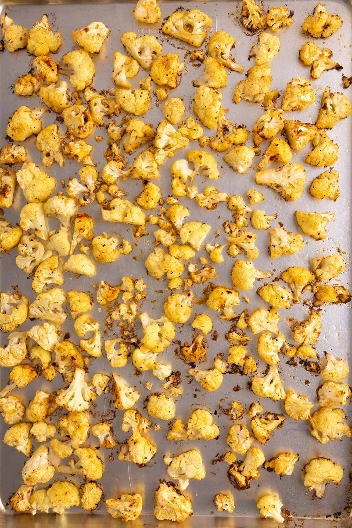 Cooked cauliflower pieces scattered on a cooking pan.
