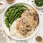 A plate of green beans, potatoes, and chicken marsala with an array of ingredients around it.