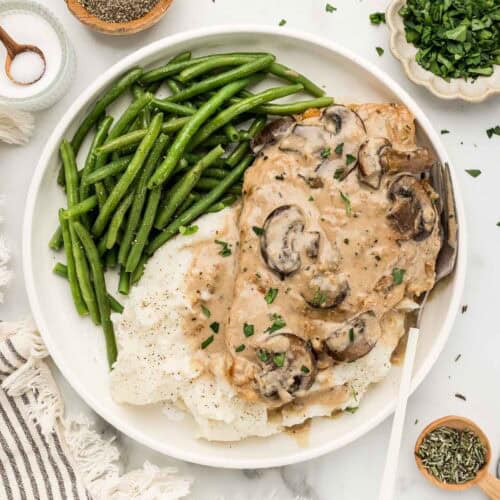 A plate of green beans, potatoes, and chicken marsala with an array of ingredients around it.