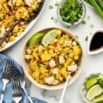 A bowl of pineapple rice with a fork and an array of ingriedients around it.