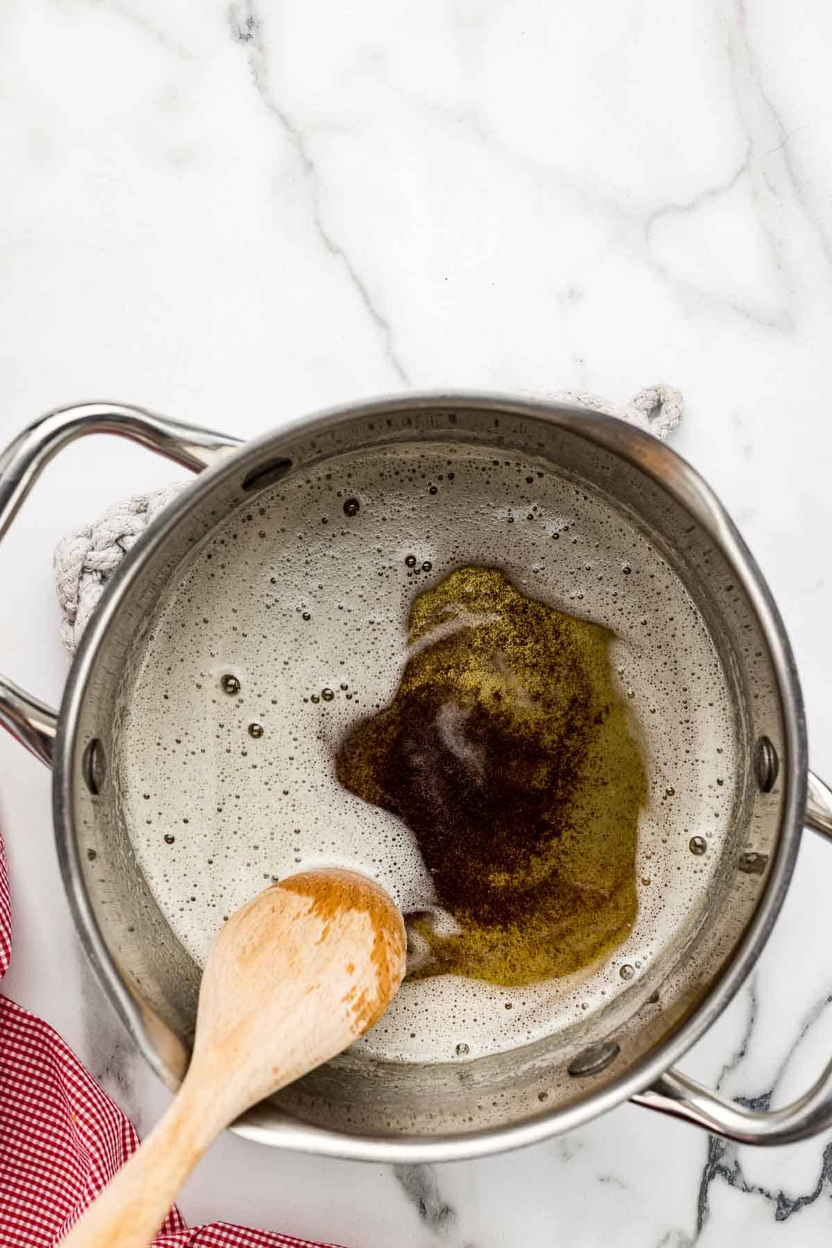 Brown butter cooking in a pot with a wooden spoon.